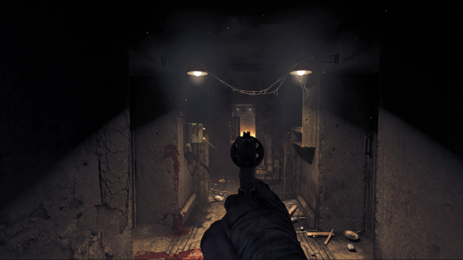 Screenshot of a first-person shooter game, showing a gun in the player's hand, pointing down at the floor inside an abandoned bunker.